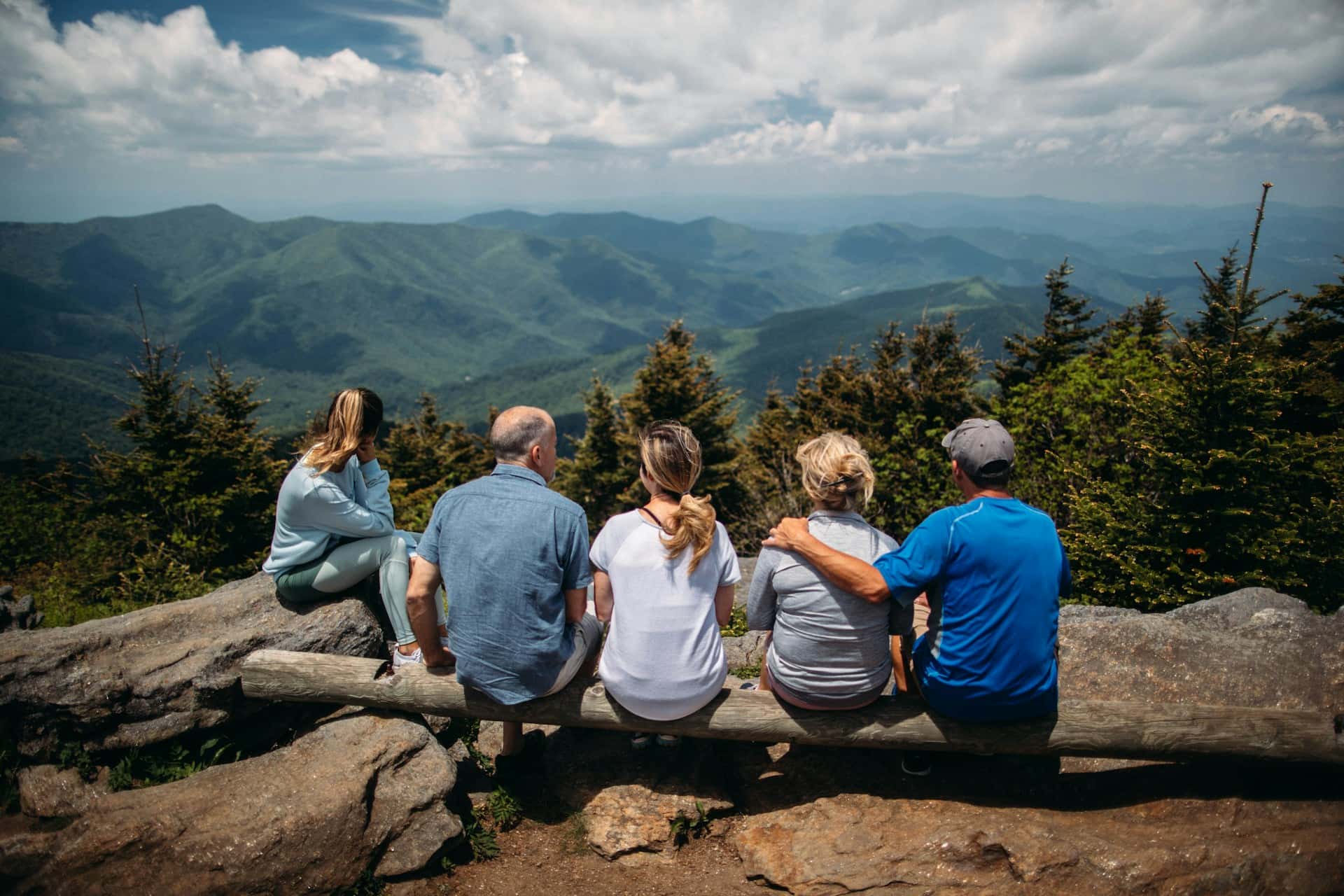 Group of people sitting on rocks overlooking mountain