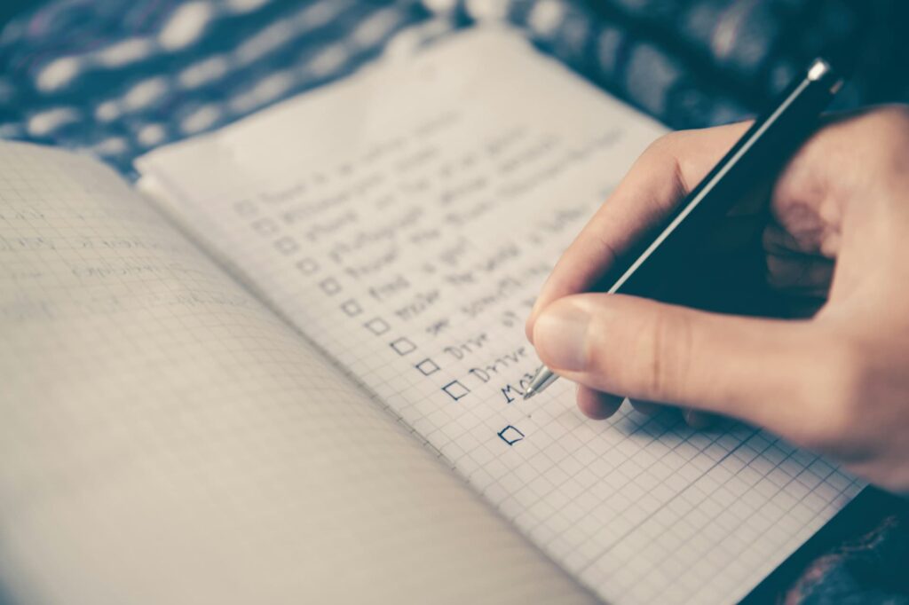 Person writing checklist on paper