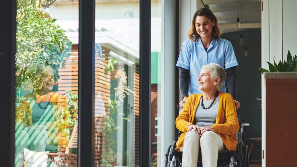 Smiling old lady in wheelchair with caretaker