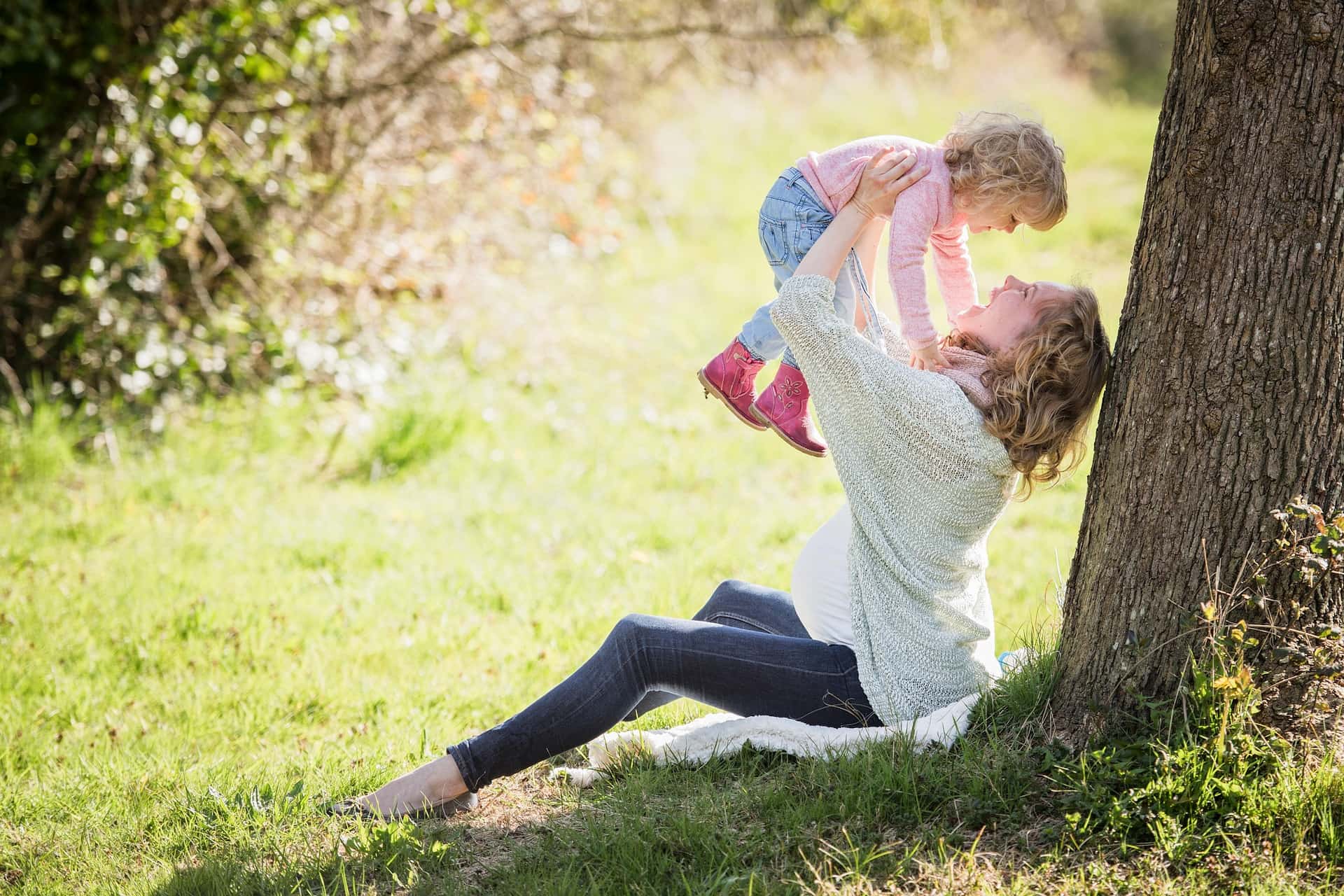 Mother throwing up girl in her arms in park