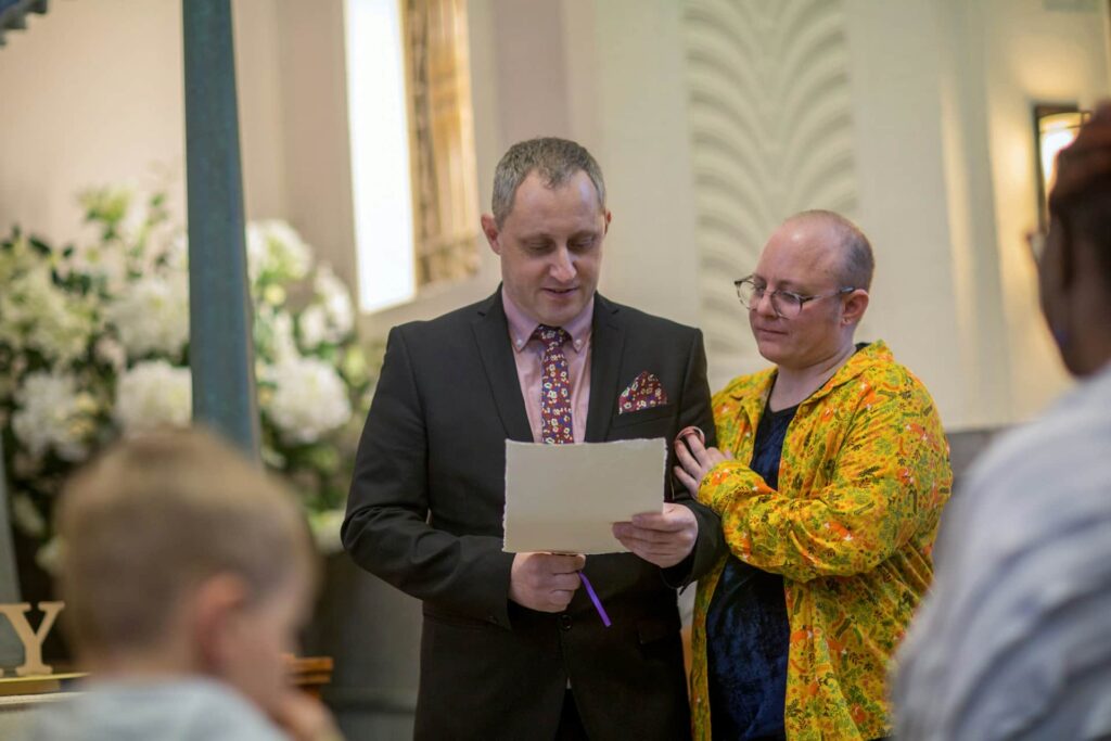 Two men read a tribute at a funeral ceremony in a crematorium chapel